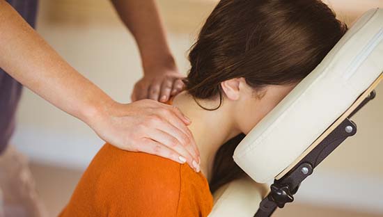 Young woman getting massage in chair in therapy room